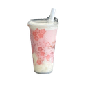 Boba tea cup decorated with pink cherry blossoms and a white straw.