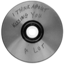 A silver CD with the handwritten text I think about kissing you a lot written on its surface.