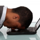 A man resting his head face down on a laptop keyboard in total exhaustion.