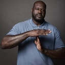 Shaquille O'Neal making a T-shaped timeout gesture with his hands against a dark background.