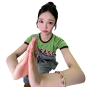 A young woman with dark hair wearing a green shirt presses her palms together in a pleading gesture.