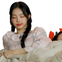 Young woman with eyes closed and a peaceful expression resting against soft bedding.