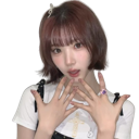 A young woman with short brown hair poses with her hands near her face in a cute expression.