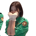A young woman in a green uniform and white gloves holding her hands to her face in a nervous, anxious gesture.