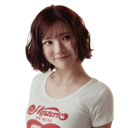 A young woman with short hair gives a playful and knowing smirk.