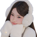 A young woman wearing fluffy white earmuffs and mittens rests her chin on her hands with a soft expression.
