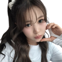 Young woman with long wavy hair looking at the camera with a soft, curious expression.