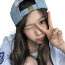 A person wearing a blue baseball cap winks and holds up a peace sign.