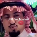 Man wearing a ghutra puckering his lips for a kiss with a red kiss mark icon.