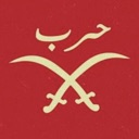 Crossed scimitars with Arabic text above them on a red background.