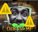 A distorted face inside a television screen with yellow warning symbols and the text LOOK AT ME.