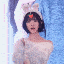 Woman wearing a bunny ear headband with a strawberry charm performs a rhythmic dance move.