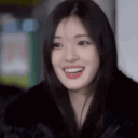 Young woman with long dark hair covering her mouth with her hand while giggling and looking away.