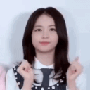 A young woman performing a rhythmic finger-gun gesture with a confident expression.