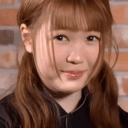 A young woman with brown hair giving an awkward, tight-lipped smile.