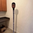 Human head attached to a long thin pole standing in a room.