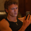 Young man with curly hair looking intensely at his smartphone screen.