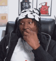 Man wearing a beanie shrugging his shoulders with a confused expression.