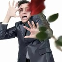 A man in a suit recoils with a shocked expression while a red rose flies toward his face.
