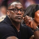 Shannon Sharpe wearing glasses looking with a skeptical and judgmental expression.