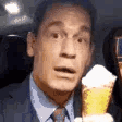 John Cena in a suit looking confused while eating an ice cream cone.