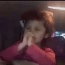 A young child with hands clasped together in a prayer-like gesture looking intently.