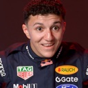 Young man in a racing suit with a wide-eyed, awkward, and surprised expression.