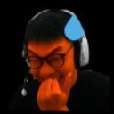 Gamer wearing headphones and glasses laughing while covering their mouth with their hand.