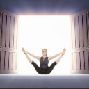 Woman performing a wide-legged yoga stretch in front of a bright, open doorway.