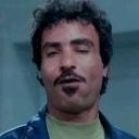 Man with a mustache and goatee looking smugly unimpressed with his eyes half-closed.