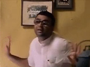 A man with glasses holds his hands up in a dismissive gesture.