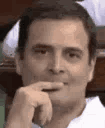 Rahul Gandhi resting his chin on his hand with a smug, knowing smirk.