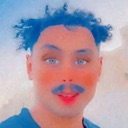 A person with a heavily filtered, distorted face and blue mustache looking directly at the camera.