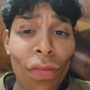 A person with dark hair making an exaggerated, pouting, and skeptical facial expression.