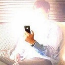 Person holding a smartphone that emits an intense, blinding white light over their face.