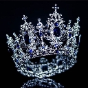A sparkling silver crown with blue jewels set against a dark background.