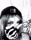 A girl wearing a beanie and skeleton-patterned gloves playfully covers her face with her hand.