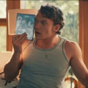 Man holding a game case up to his face with a confused and curious expression.
