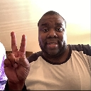 A man looking at the camera and holding up a peace sign with his hand.