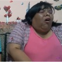 A person with eyes closed and mouth wide open in a contorted facial expression.