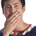 A man covering his mouth with his hand while smirking mischievously.
