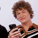 Man looking down at his smartphone with a smug, skeptical, and unimpressed facial expression.