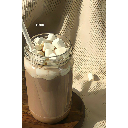 Hot chocolate in a glass topped with marshmallows sits on a wooden coaster.