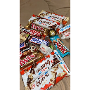 A messy pile of various chocolate bars and snack wrappers stacked together.