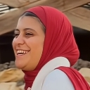 Woman wearing a red hijab laughing with a bright and genuine expression.