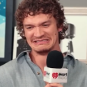 Man making a disgusted, cringing face while holding an iHeartRadio microphone.