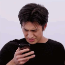 Man squinting at his smartphone with a confused and disgusted facial expression.