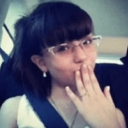 Person with glasses blowing a kiss towards the camera.