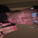 A person wearing glasses takes a close-up, slightly blurry selfie with their hand held up.