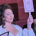 Woman holding up a scorecard with the number ten written on it.